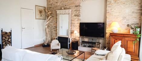 Una sala de estar con pared de piedra, chimenea, televisor y sofá.