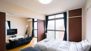 Camera d'albergo moderna con un letto grande, una scrivania con televisore a schermo piatto e un angolo salotto con pouf.