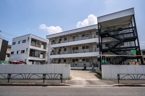 Un edificio a più piani con balconi, una scala e un ingresso carrabile.