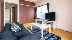 Un ambiente compatto con un divano, una televisione, un tavolino e un armadio.