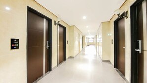 Un pasillo de hotel con varias puertas, cada una con una pantalla digital que indica el número de habitación 608.