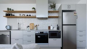 A modern kitchen with white cabinets, a stainless steel refrigerator, and wooden shelves. - South Launceston – Easy & Comfortable (Launceston City)