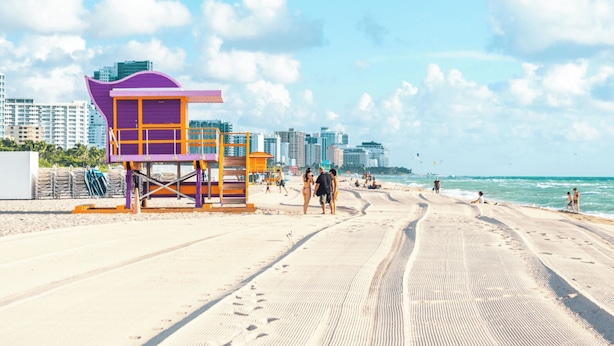 Ein Strand mit einem Rettungsturm, Sand und Wellen.