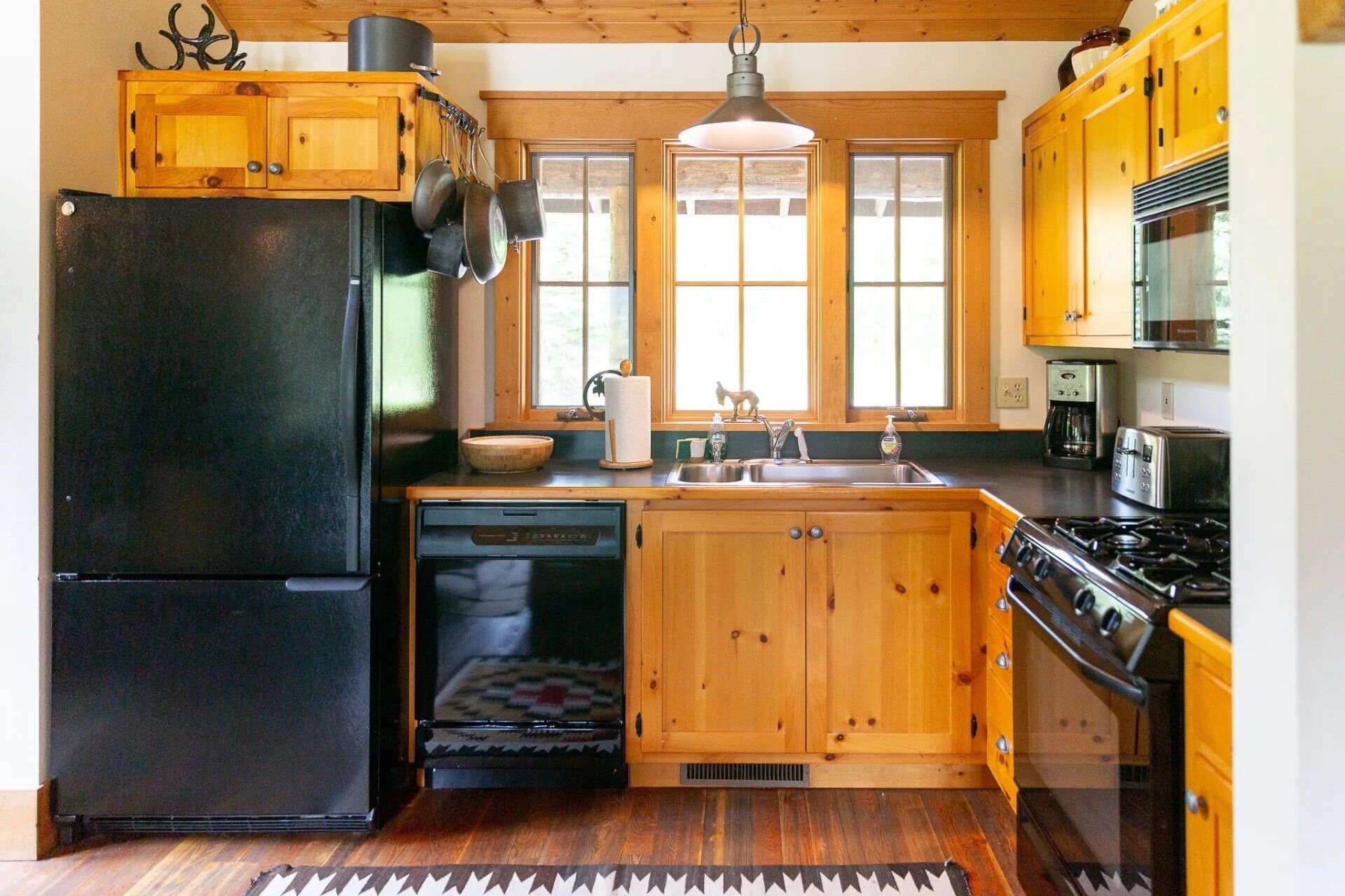 A kitchen with wooden cabinets, a black refrigerator, a stove, and a dishwasher.