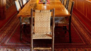 A wooden dining room with a long table, chairs, and a chandelier.
