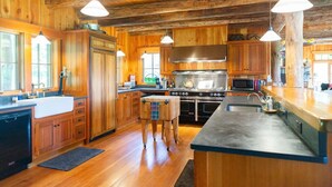 A spacious kitchen with wooden cabinetry, a large stove, and pendant lighting.