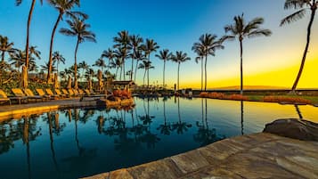 A pool with lounge chairs and palm trees.
