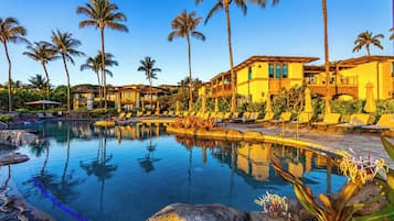 Ein Resort mit Pool, Palmen und einem Gebäude mit mehreren Balkonen.