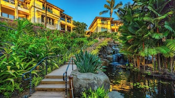 A hotel with a pool, surrounded by tropical plants and a waterfall.