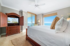 A bedroom with a large bed, a wooden dresser, a ceiling fan, and a view of the ocean. - Indigo 1703E | New Rental | Beachfront | Free Beach Service (Pensacola)