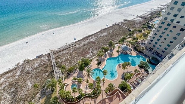 Een resort met uitzicht op het strand, een zwembad en een hoog gebouw.