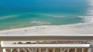 Een strand met helder uitzicht op de oceaan en een witte balustrade op de voorgrond.