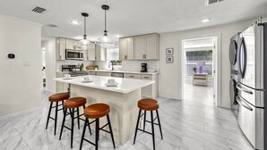 A modern kitchen with a central island, bar stools, stainless steel appliances, and pendant lighting. - Full Duplex on Longboat Key, Walk to the Gulf + Cedars East Club Access (Longboat Key)