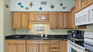 A kitchen with wooden cabinets, a granite countertop, a microwave, and a stove. - Ideal location - 2bed/1bath near the beach & shops (Port Charlotte)