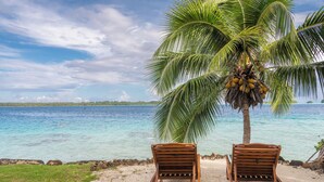 Two wooden lounge chairs facing a beach with a palm tree and clear blue water. - Paradise (Bora Bora)