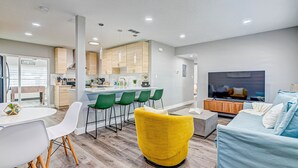 Un salon moderne avec un fauteuil jaune, un canapé bleu et un téléviseur.