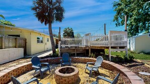 Un patio trasero con un brasero, mobiliario exterior y una terraza de madera.