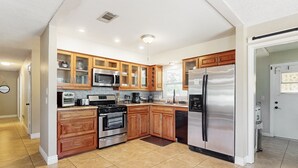 Una cocina moderna con armarios de madera, electrodomésticos de acero inoxidable y piso de baldosas.