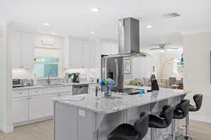 Une cuisine moderne avec des meubles blancs, un réfrigérateur en acier inoxydable et un plan de travail en marbre.