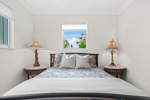 Une chambre à coucher avec un lit, deux lampes de chevet, une fenêtre donnant sur un beau paysage et une table de chevet avec une lampe.
