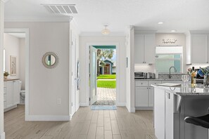 A modern kitchen with white cabinetry, a built-in oven, and a view to the outside. - Cocoa Beach Riverfront Retreat — Screened Porch, Wildlife Views & Short Drive to the Beach! 🌅 (Cocoa Beach)
