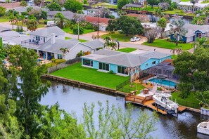 A residential area with houses, a dock, and a boat. - Cocoa Beach Riverfront Retreat — Screened Porch, Wildlife Views & Short Drive to the Beach! 🌅 (Cocoa Beach)
