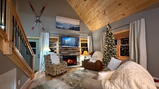 Un salon chaleureux avec une cheminée, un sapin de Noël et un téléviseur.