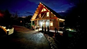 Une maison en bois avec un porche et une allée, de nuit.