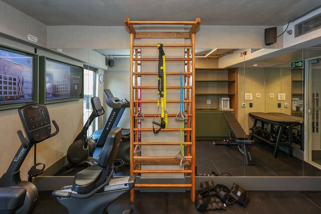 Un gimnasio con equipo de ejercicio, una barra de dominadas y una cinta de correr.