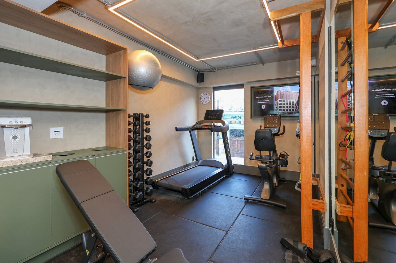 Un gimnasio con cinta de correr, banco para pesas y diverso equipamiento de ejercicio.