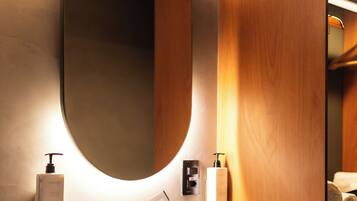 Une salle de bain moderne avec un grand miroir ovale, un lavabo en marbre et un lambris en bois.