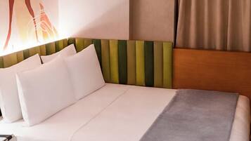 Quarto de hotel moderno com cama, cabeceira com listras verticais, mesa de cabeceira e luminária fixada na parede.