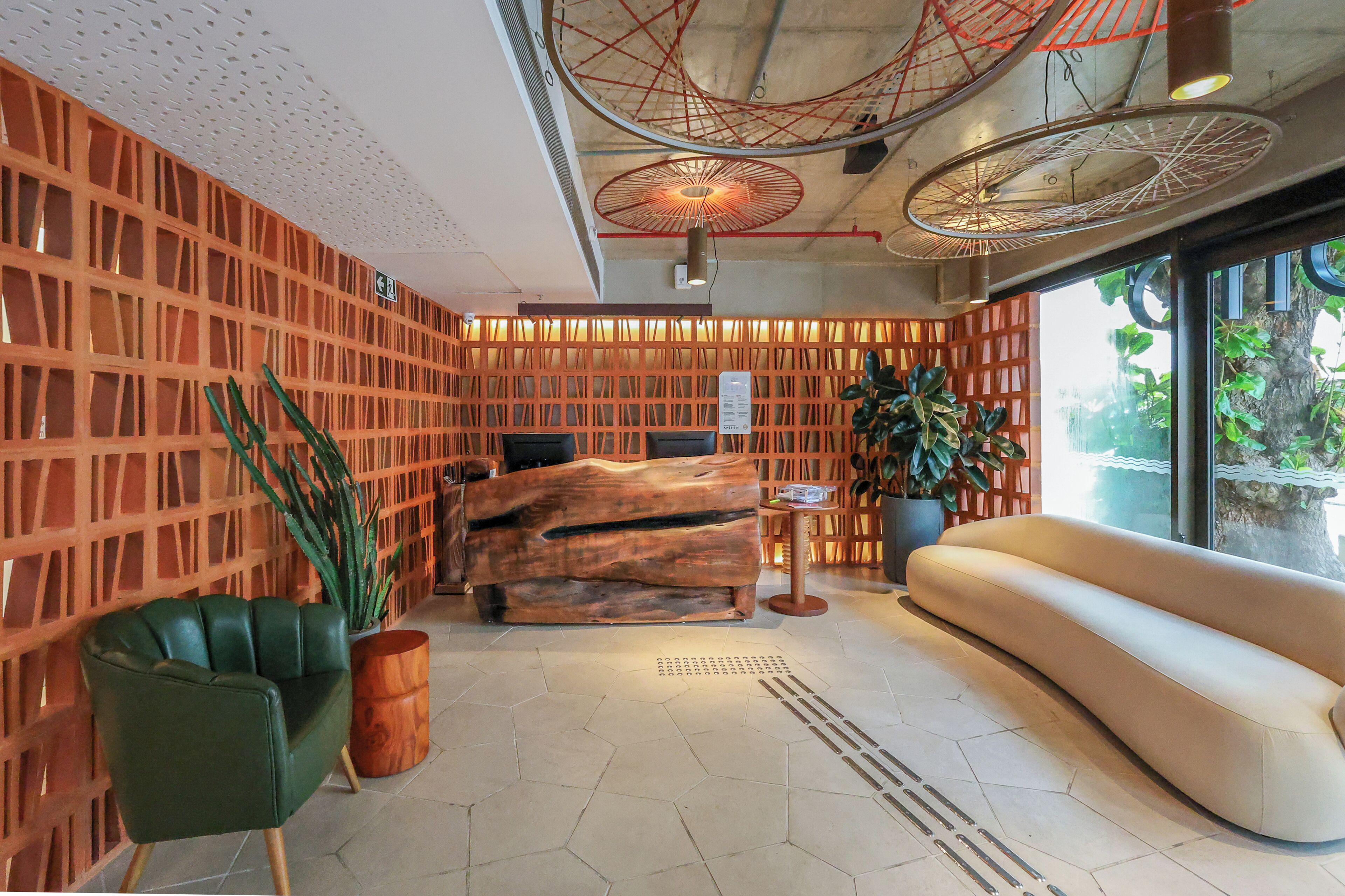 Un interior moderno con un separador de madera, una silla verde, un sofá y una planta.