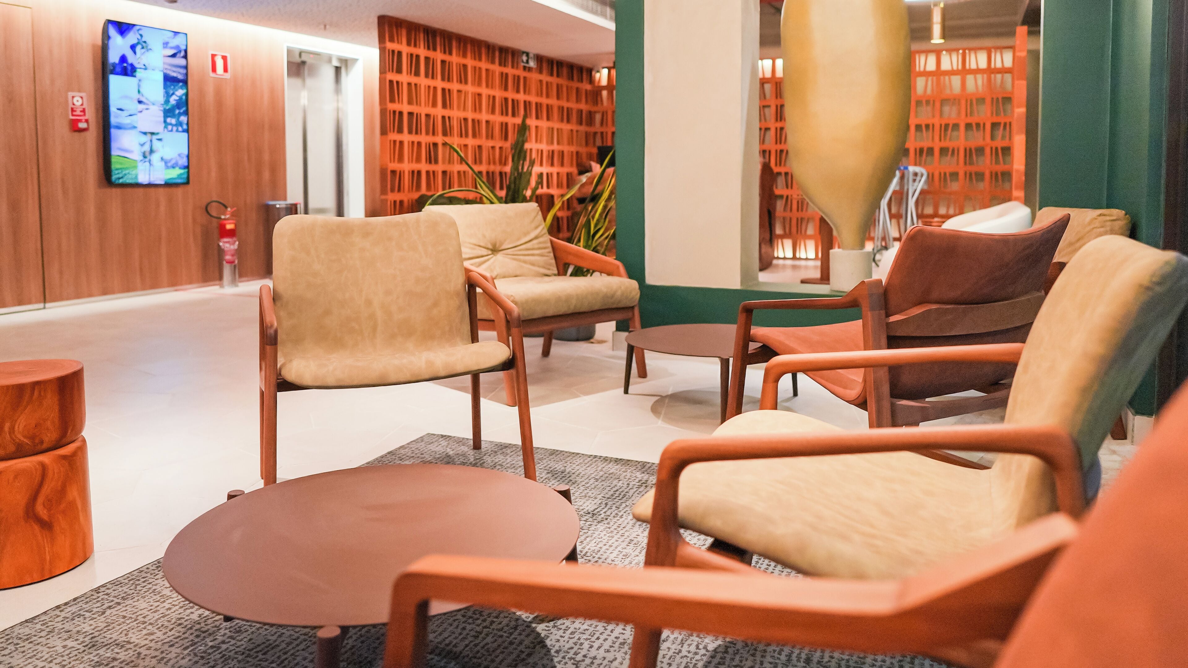 Um lobby moderno com área de estar, mesa de centro e televisão fixada na parede.