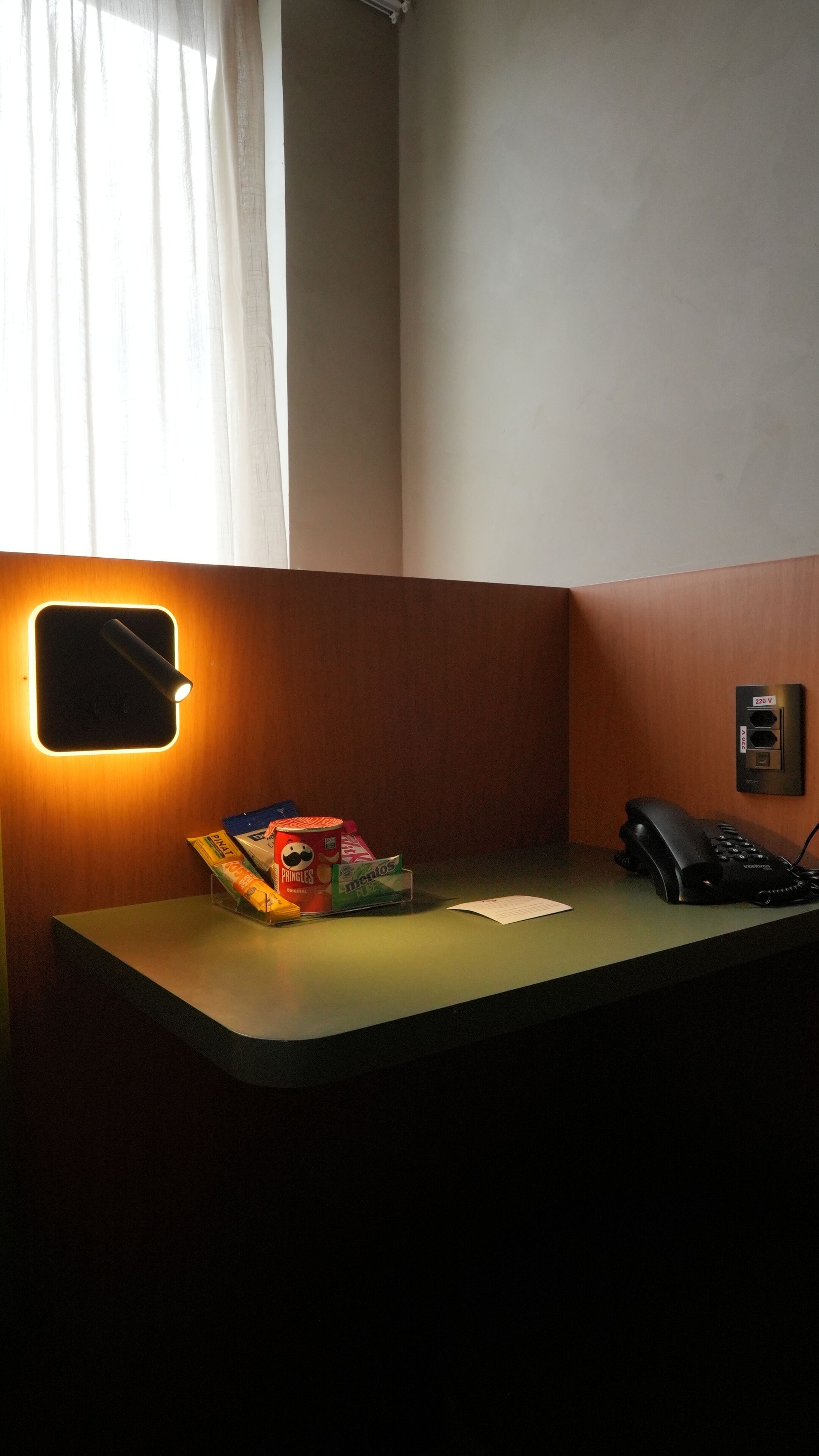 A hotel reception desk with a telephone, a small desk lamp, and a snack dispenser.