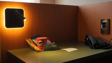 A hotel reception desk with a telephone, a small desk lamp, and a snack dispenser.