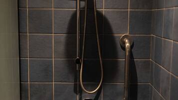 A shower with a handheld showerhead and a wall-mounted faucet.