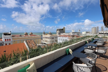 A rooftop terrace with outdoor seating, a view of the cityscape, and a clear sky.. Motto By Hilton Recife