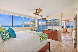 A bedroom with a large bed, a ceiling fan, and a view of the ocean through large windows. - Spectacular ocean views at Spacious 2-BR AC Pool- Royal Kahana 610 (Lahaina)
