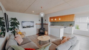 Un salon moderne avec un canapé, une table basse et une cheminée. Il y a également un coin cuisine avec des meubles en bois et une fenêtre.