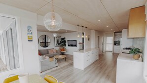 Un salon moderne avec un canapé, une table basse et un coin repas. On y trouve également une cuisine avec des meubles blancs et une table à manger.