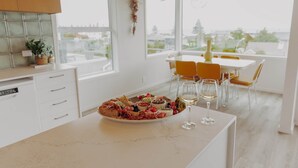 Une cuisine moderne dotée d’un grand îlot central, de meubles blancs et d’un coin repas avec une table et des chaises.
