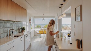 Une cuisine moderne dotée d’une grande fenêtre, de meubles en bois et d’un plan de travail sur lequel sont disposés divers objets.
