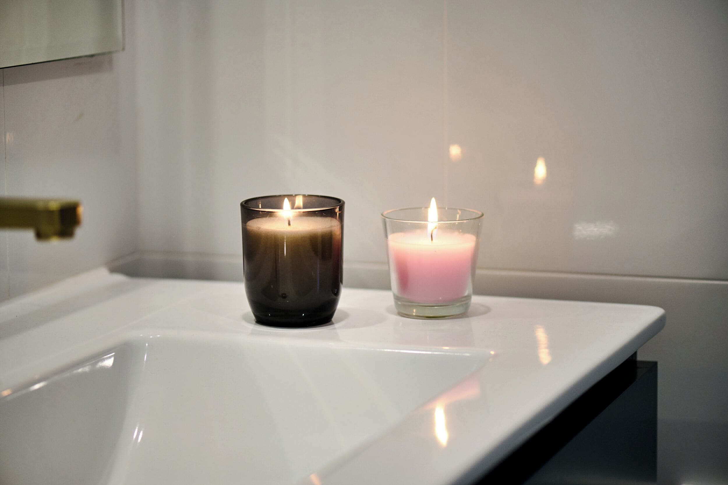 Two lit candles on a white sink.
