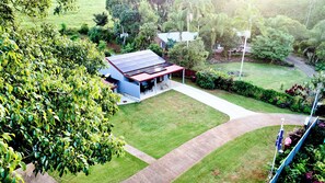 A house with a solar panel roof, a covered patio, and a well-maintained lawn. - Malanda Falls Retreat (Upper Barron)