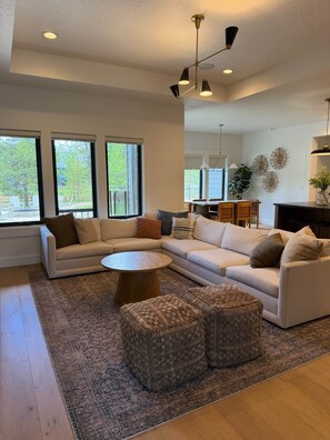 A modern living room with a sectional sofa, a round coffee table, and a patterned rug. - Cabin w/Hot Tub & Bunk Room - Steps to the lake! (Valley County)