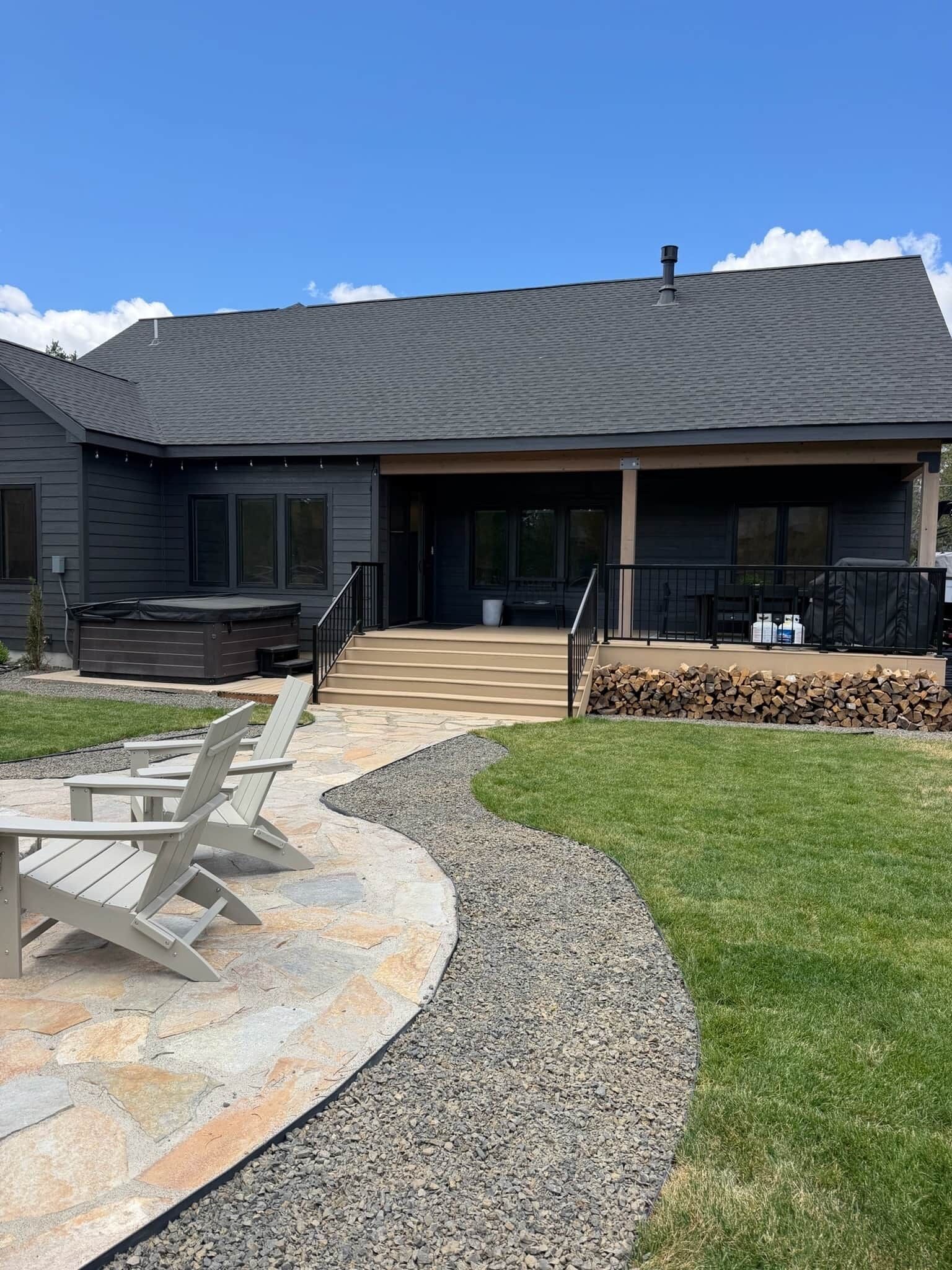 Une maison moderne dotée d’un patio en pierre, d’un espace salon extérieur et d’une zone abritée.