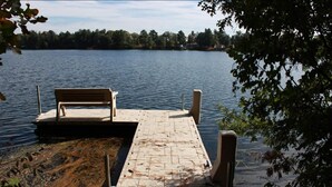 A wooden dock extending into a calm lake, surrounded by trees. - Delightful 3-bedroom cabin on Big Roche Cri Lake in charming Friendship, WI! (Friendship)