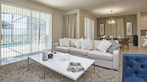 A modern living room with a beige sofa, a white coffee table, and a blue armchair. - Storey Lake 6 Bedroom Vacation Home 4712 (Osceola County)