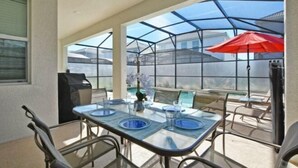 A covered patio with a glass table set for dining, surrounded by chairs. - Storey Lake 6 Bedroom Vacation Home 4712 (Osceola County)